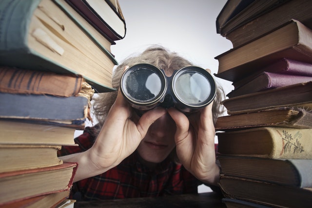 Frau mit Fernglas zwischen Büchern