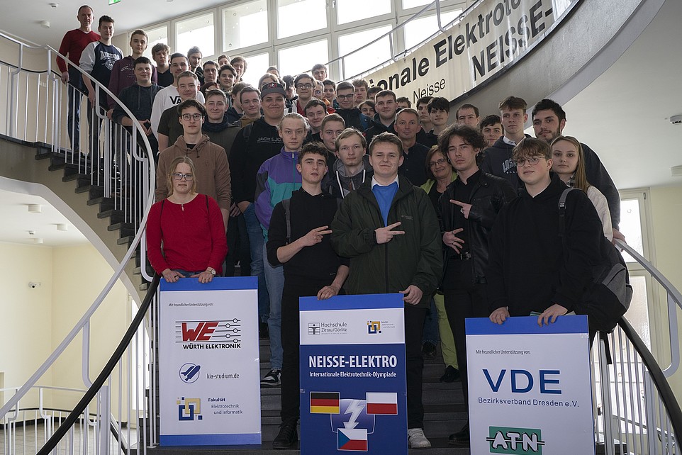 Eine Gruppe von Schülern steht auf einer Treppe. Die vorderen halten drei Plakate mit den Werbepartnern und dem Logo der Neisse Elektro