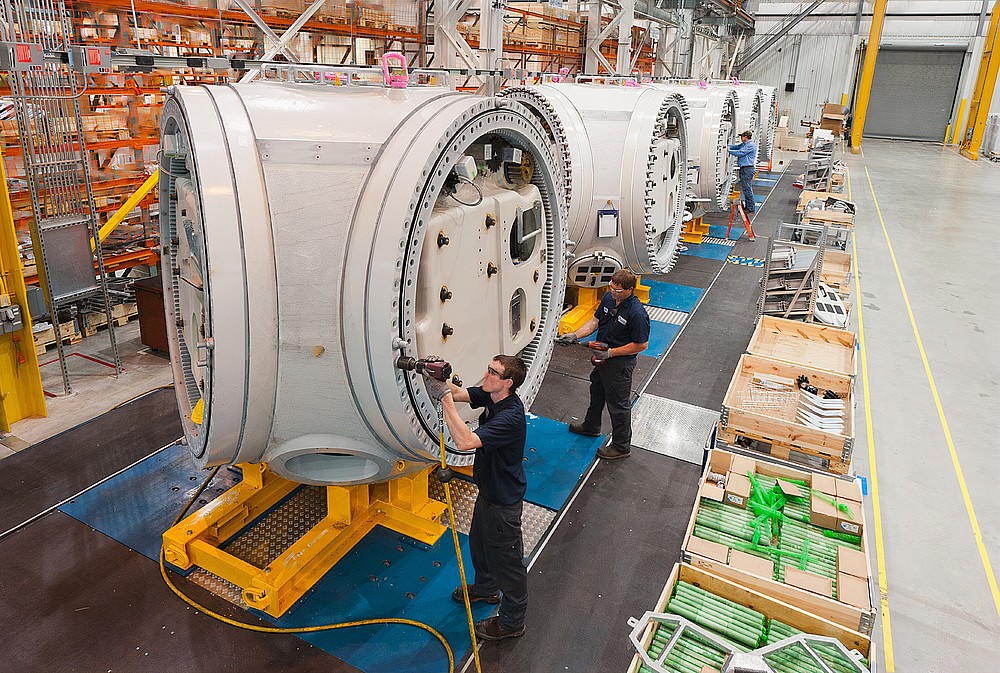 Fertigungsstätte -  Menschen arbeiten an einzelnen Windräderteilen