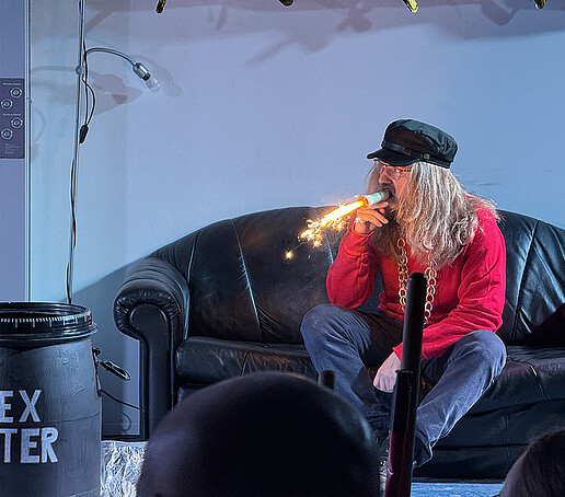 Ein Darsteller zündet sich einer feuersprühende Zigarre an.