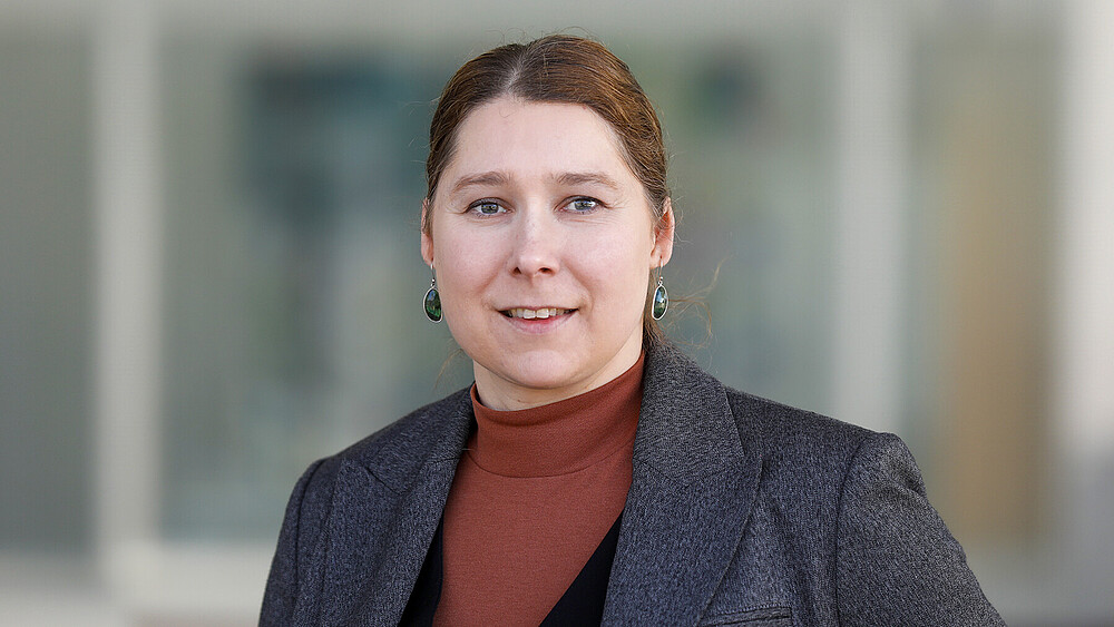 Prof. Dr. rer. nat. Elisa Wirthgen steht vor einem Gebäude und lächelt in die Kamera.