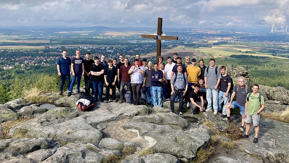 Ein Panoramablick vom Töpferberg zeigt die beeindruckende grüne Landschaft. Neben einer Wandergruppe sind Felsformationen zu sehen.