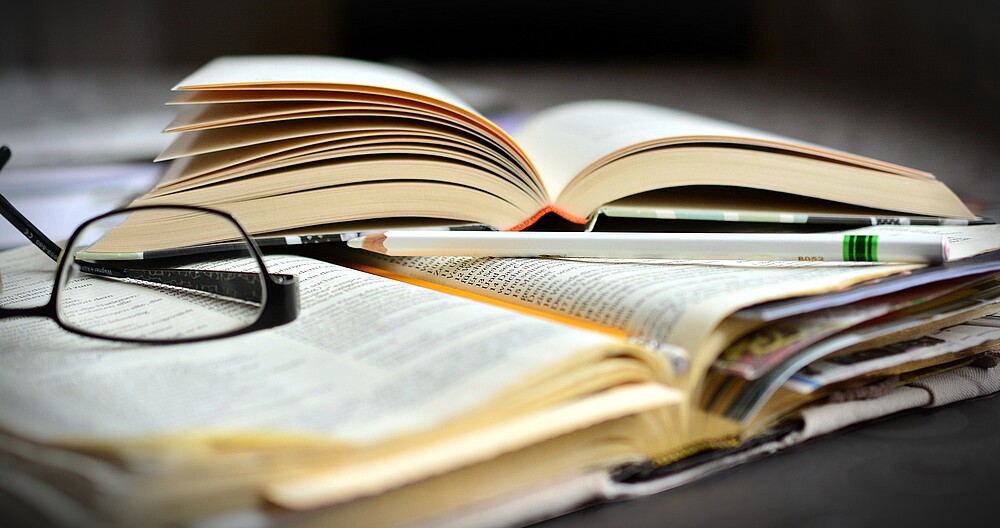aufgeschlagene Bücher und Brille