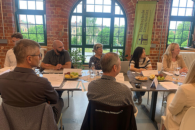 Gäste des Treffens sitzen im Celsiuz an einer langen Tafel und schauen alle in eine Richtung.