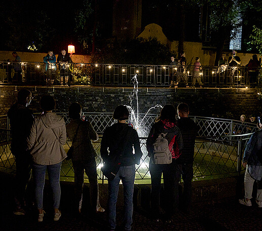 Besucherinnen und Besucher stehen am Schleifermännchen-Brunnen.