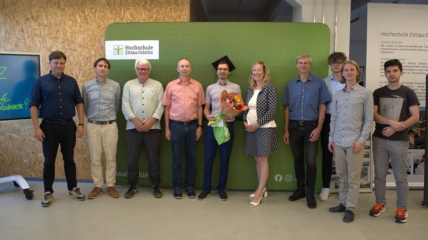 Eine Gruppe von Forschenden stehen nebeneinander vor einer grünen HSZG-Pressewand und lächeln in die Kamera.