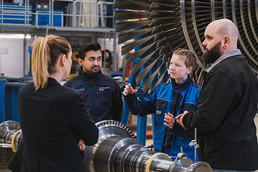 Vier Personen vor einer Industrieturbine