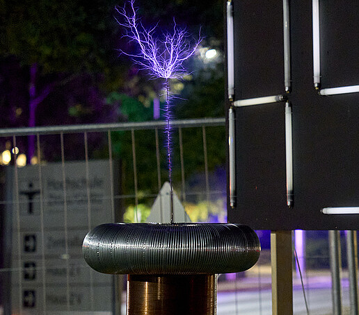 Das HSZG-Logo leuchtet hell, im Vordergrund ist ein lila Blitz zu sehen.