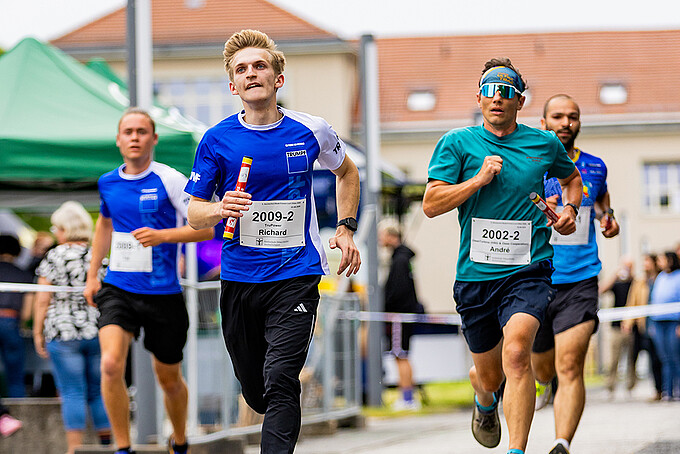 Laufteilnehmende rennen an der Campusachse entlang.