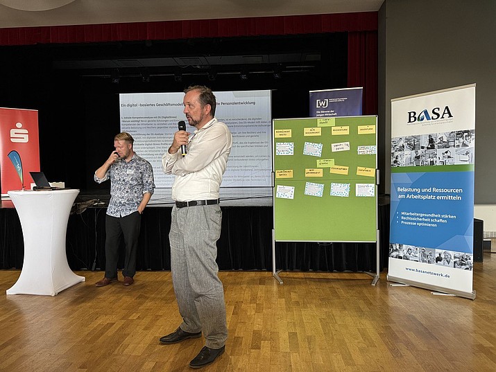 Tino Schmidt und David Sauer beim UFO-Workshop. Beide stehen vor Aufstellern. David Sauer hält ein Mikro in der Hand.