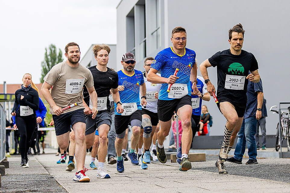 Laufteilnehmende rennen an der Campusachse entlang.