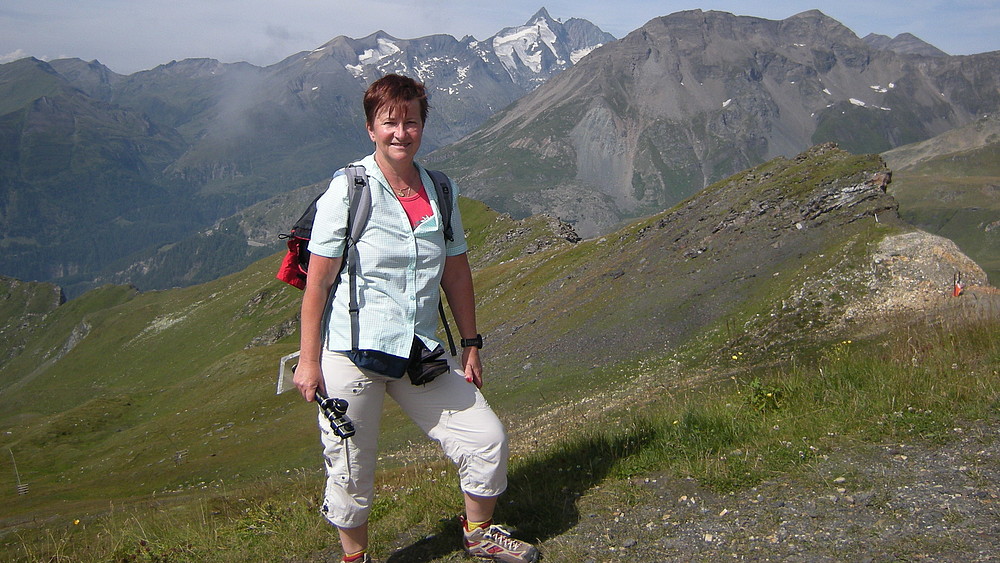 Prof. Spangenberg auf einer Wiese. Im Hintergrund sind hohe Berge zu sehen.
