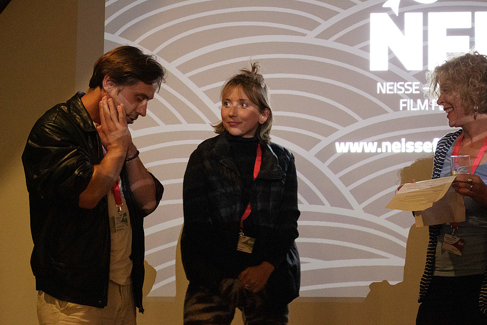 Festivalorganisatoren unterhalten sich vor einer Wand mit einer NFF-Projektion.