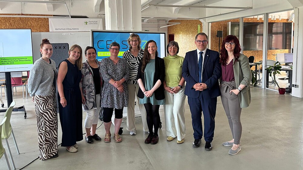 Die Mitarbeiterinnen im Professorinnenprogramm stehen mit dem Rektor im Celsiuz zum Gruppenfoto in einer Reihe und lächeln in die Kamera.