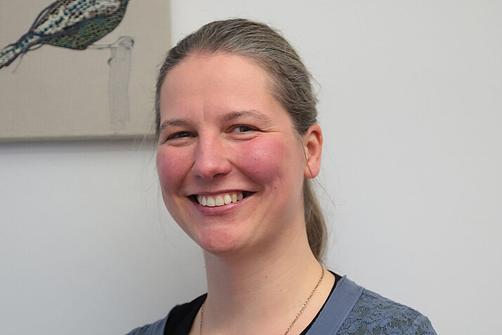 Sabine Bublitz im grauen Shirt mit blondem Zopf lächelt in die Kamera.