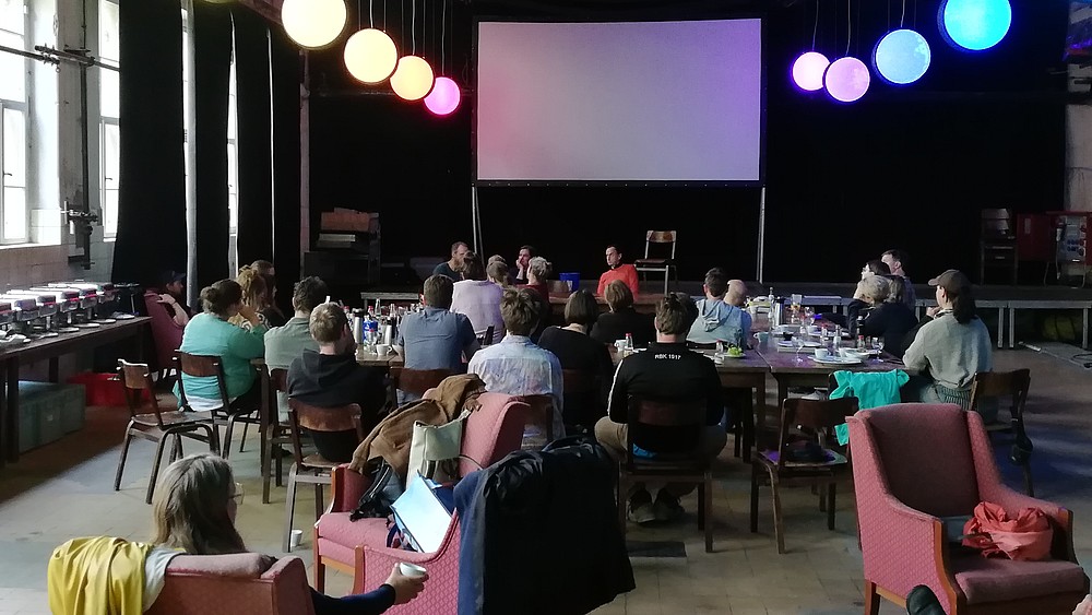 Alumni and HSZG employees sit at tables in a room in the Kulturhaus and exchange ideas.