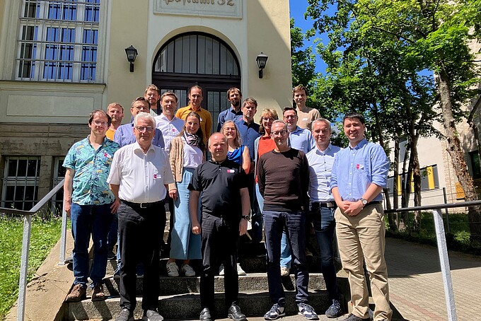 Mitglieder des Bündnisses EdgeVision stehen auf dem Treppenabsatz vor einem Gebäudeeingang nebeneinander zum Gruppenbild.