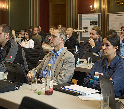 Das Publikum richtet seinen Blick nach vorn zu den Vortragenden.